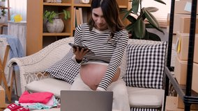 Asian pregnant woman online business entrepreneur show children clothes products, pregnancy mom make a note delivery full of cardboard box, expectant girl vlogger facing camera sell baby dress - Powered by Shutterstock - Get 15% off with code: PIKWIZARD15