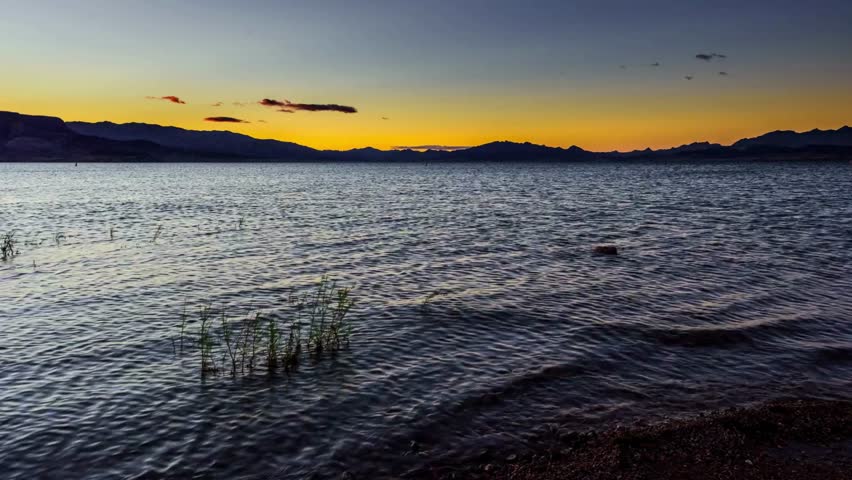 Serene Sunset Over Calm Lake Water with Mountain Silhouette