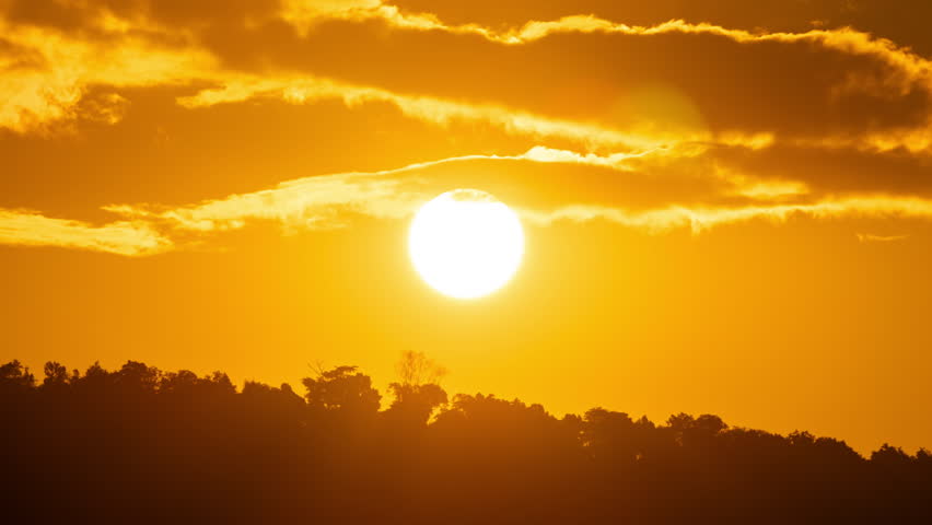 Time lapse of the sun rising over hills that are covered with clouds, in the style of smokey background.