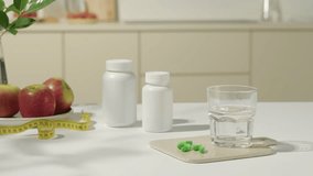 Hands from outside reached in to take out green pills. The pills were effective in weight loss and digestive balance. Yellow measuring tape, red apple plate and two unlabeled pill bottles. - Powered by Shutterstock - Get 15% off with code: PIKWIZARD15