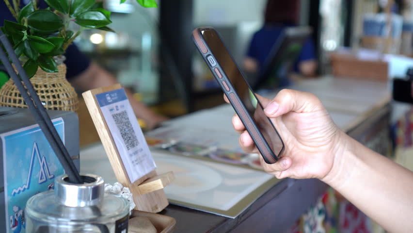 Close-Up of a customer using a smartphone to scan a QR Code for cashless payment at a café ,convenience of online transactions and e-wallet technology
