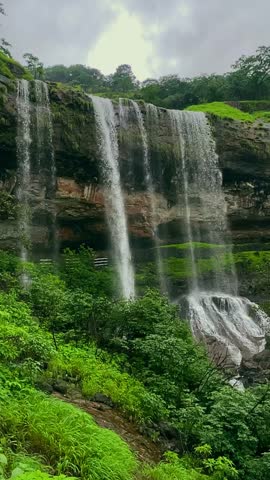 A breathtaking view of majestic waterfalls cascading through lush green forests in Bhandardhara, Maharashtra, India. Water crashes over rugged cliffs, creating a mesmerizing natural paradise 4K