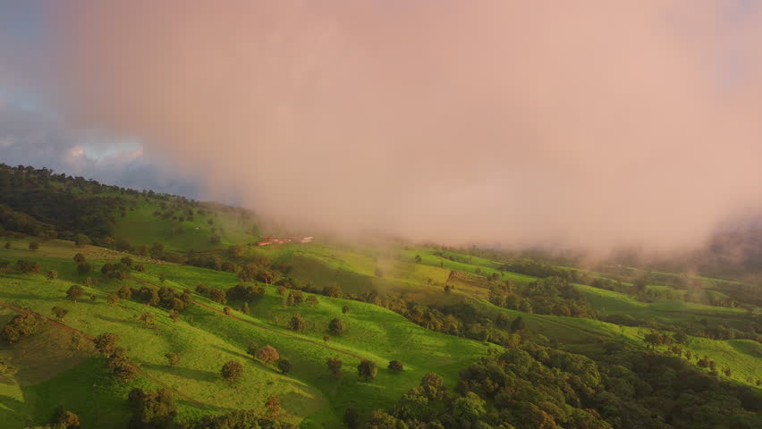 Experience the breathtaking and stunning aerial views of Costa Rica as a soft mist blankets the lush, vibrant green hills during a beautiful sunrise, showcasing natures tranquil and serene beauty