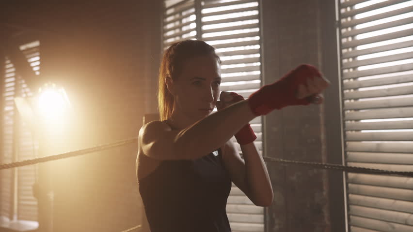 Portrait of athletic woman in pose for punching in boxing club, self-defense. Sports for stay healthy and beautiful, femininity and masculinity, motivated confident sportswoman in static position