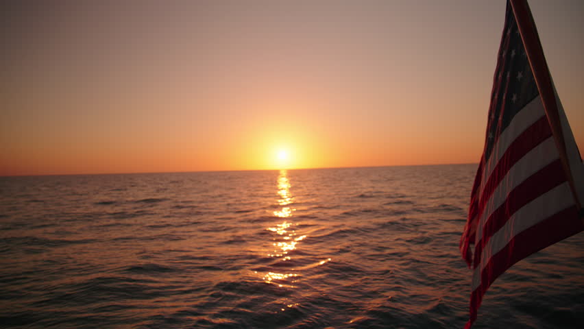 Experience the stunning beauty of a majestic sailing ship with an American flag at sunset in Key West, Florida. This tranquil moment is beautifully captured in slow motion for all to enjoy