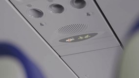 Close up Fasten seatbelt sign turns on during airplane flight requesting passengers to buckle up their safety belt and return to seat. Safety announcement lights up or symbol appearing overhead - Powered by Shutterstock - Get 15% off with code: PIKWIZARD15