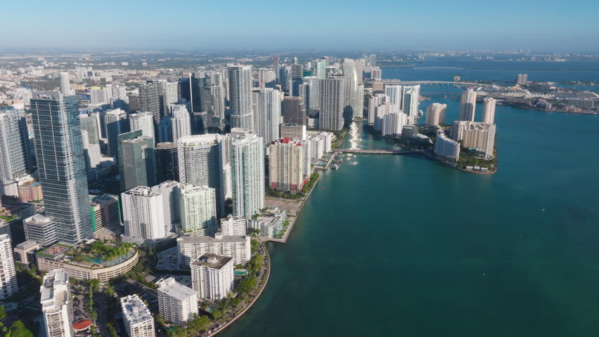 Stunning aerial shots of Downtown Miami and Brickell Key beautifully showcase the impressive modern skyscrapers along with captivating waterfront views, all under the bright and vibrant sunrise