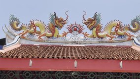 Close-up of Colorful Chinese Temple Roof Decoration with Two Facing Dragons and Shining Sun Symbol. Ornate Taoist Architecture Element Against Bright Blue Sky. Traditional Religious Art on Pagoda Top. - Powered by Shutterstock - Get 15% off with code: PIKWIZARD15