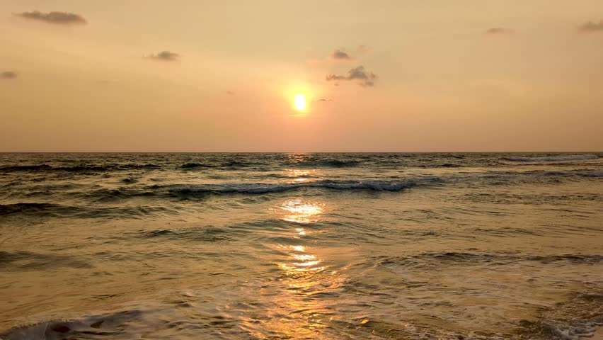 Stunning golden sunset reflecting over ocean water with waves rolling into beach, Hikkaduwa, South Coast Sri Lanka