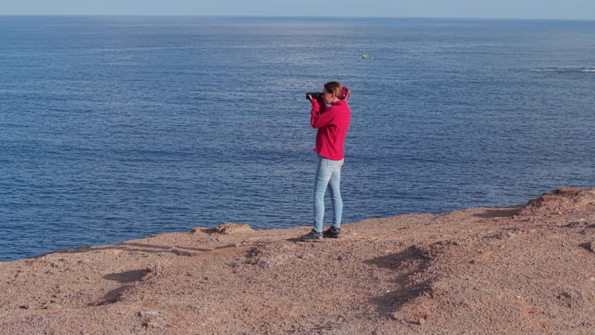 Aerial view of woman photographer taking pictures of Roque partido and the ocean in Gran canaria, canary islands