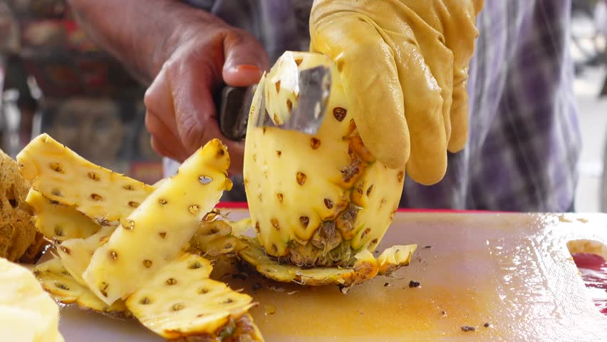 hand in yellow gloves cutting Pineapple