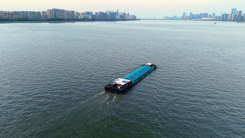 Barge navigating the river waters of China during a calm day.