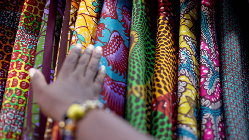 Small business owner of an African Print, Ankara fabric shop proudly displaying different kinds of textile prints.
