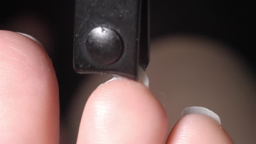 Low-angle close-up showing small toes having nails trimmed with a black clipper tool