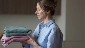 Happy woman enjoying fresh laundry holding soft folded clothes simple pleasure for cozy satisfaction - Powered by Shutterstock - Get 15% off with code: PIKWIZARD15