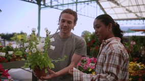Smiling multi ethnic couple selecting pristine white flowers at garden center, inhaling fragrance and sharing intimate moment together - Powered by Shutterstock - Get 15% off with code: PIKWIZARD15
