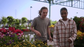 Garden center customers carefully examining and gently smelling white flower bouquet while standing among vibrant, colorful plants during seasonal shopping experience - Powered by Shutterstock - Get 15% off with code: PIKWIZARD15