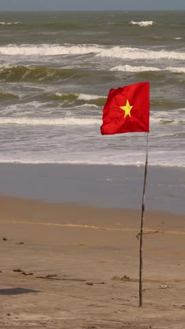 The flag of Vietnam waves against the backdrop of the sea.