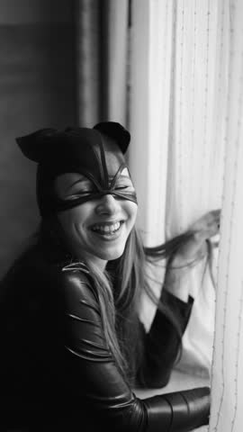 vertical video. Young woman wearing a cat mask by the window. costumes for erotic games. feminine attractiveness.
