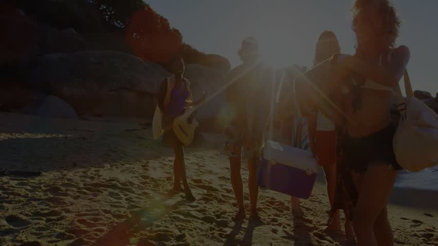 Friends unfolding patterned blanket on beach at dusk, projecting neon palm patterns for tech demo. Beach, lifestyle, vibrant, entertainment, summer, relaxation, social