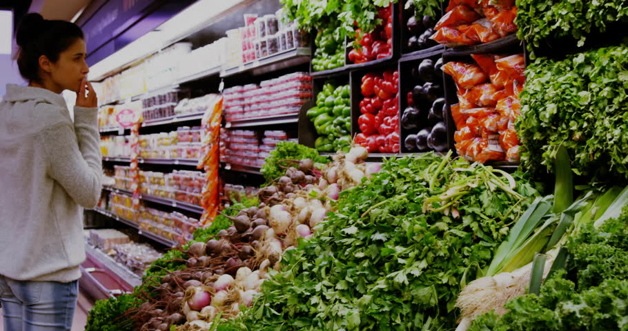 Woman contemplating fresh produce in retail marketing, with floating price tags and data charts. Freshness, shopping, healthy, contemporary, vibrant, consumer, organic