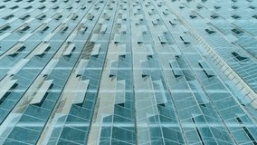 Glass building facade featuring angled windows, showing digital bar charts, code and globe icons. Architecture, urban, modern, reflective, minimalist, technology, enterprise - Powered by Shutterstock - Get 15% off with code: PIKWIZARD15