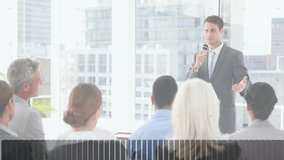 Male presenter holding microphone at podium in business meeting, displaying digital graph overlays. Corporate, innovation, professional, analytics, teamwork, modern, strategy - Powered by Shutterstock - Get 15% off with code: PIKWIZARD15