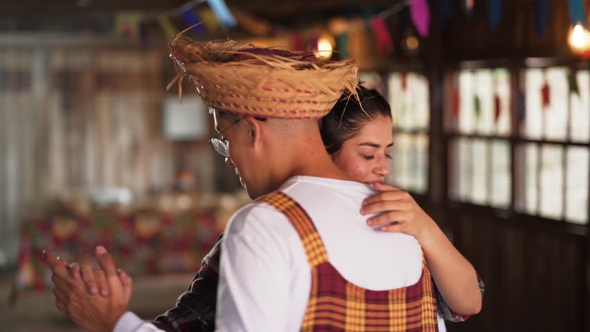 Tender Embrace Shared Between Dancers at Brazilian Cultural Fest. Man in Traditional Hat holding Partner in Vibrant Dress at Festa Junina Dance