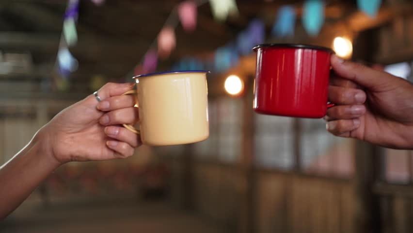 Symbolic Toast with Colorful metal Mugs at Brazilian June Festivities. Hands Uniting in Festive Celebration with Traditional Drink at Festa Junina