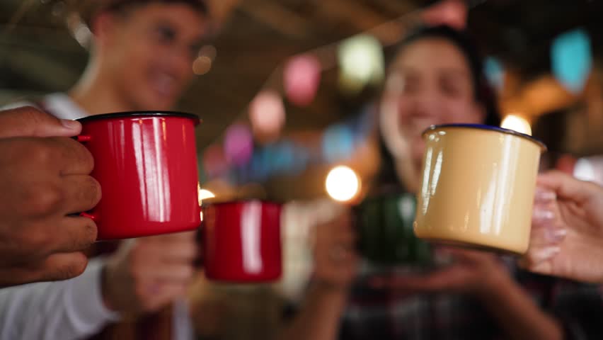 Close-Up Celebration with Steel Mugs at Brazilian June Festival Toast. Friends Raising Colorful Cups in a Festive Salute at Festa Junina Gathering