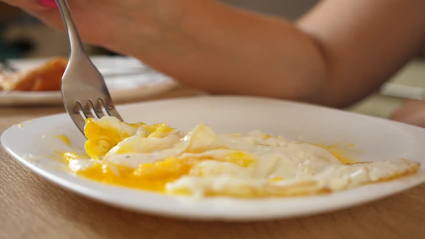 Woman eating scrambled eggs at the table at home