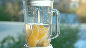 Blender turned on and mixing fresh oranges to make juice. Slicing and blending citrus fruits for a natural cocktail. Preparing an organic fruit drink. Healthy lifestyle and clean nutrition - Powered by Shutterstock - Get 15% off with code: PIKWIZARD15