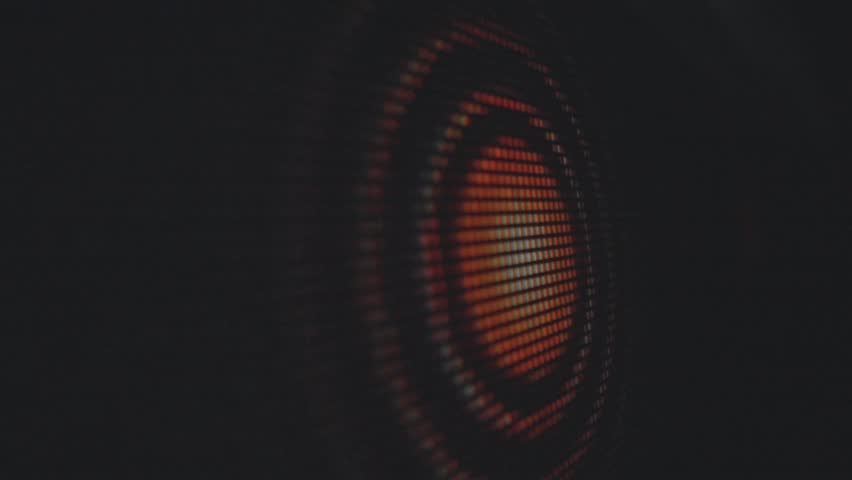 An abstract close up view of a speaker cone with vibrant orange lights, highlighting the mesh texture and circular design. Macro