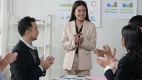 A woman in a business suit claps her hands while standing in front of a group of people - Powered by Shutterstock - Get 15% off with code: PIKWIZARD15