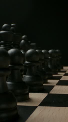 Image of black chess pieces on a chessboard, ideal for illustrating strategy and competition in gamerelated concepts. Vertical shot.