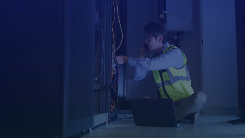 Technician inspecting network cables in IT server room, holographic overlay displaying line graphs. Technology, cybersecurity, infrastructure, digital, innovation, futuristic, industrial - Powered by Shutterstock - Get 15% off with code: PIKWIZARD15