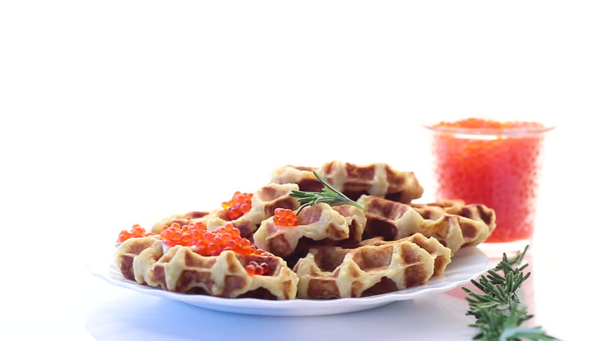 Potato waffles with red caviar on a white background