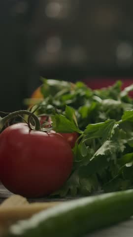 Camera zooming in to container with hot instant noodles and various herbs and vegetables in kitchen. Vertical shot.