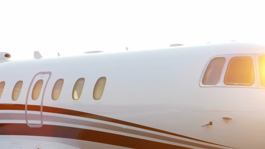 Private jet fuselage catching sunrise glare, featuring red gray accent stripes and green glitch. Luxury, aerospace, technology, aviation, sleek, modern, corporate