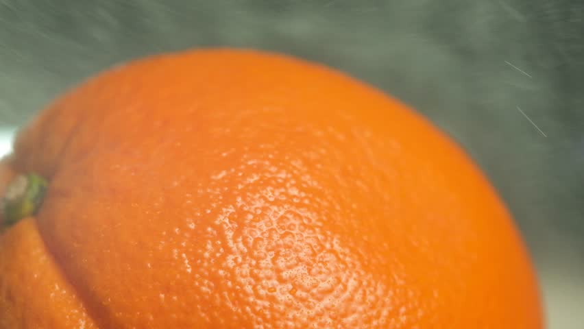 Macro shot of a stream of tiny splashes scattering across the peel of a fresh orange in slow motion. Vivid citrus texture and freshness. Visualizing flavor and energy. Ideal for juice and fruit ads