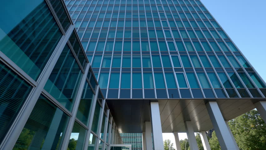 Office building with mirror glass facade in urban downtown low angle shot. Office center multi storey tower on city street. Industrial real estate