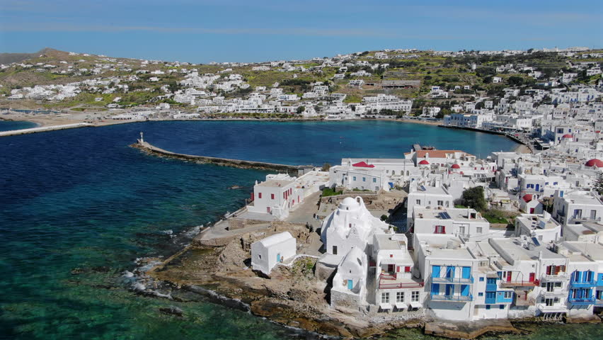 Aerial views of Mykonos showcase charming white structures contrasting with the vibrant blue Aegean Sea, creating a picturesque scene ideal for travelers seeking beauty and relaxation