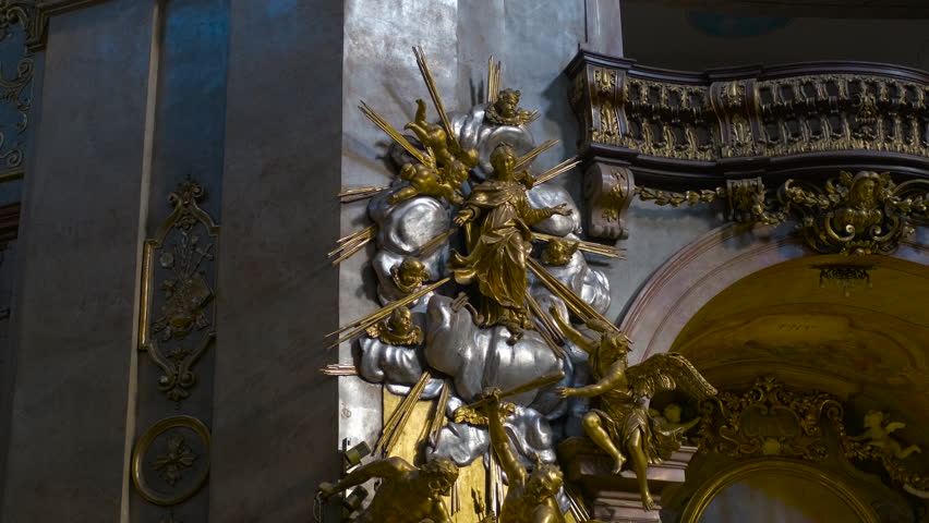 Sunlight illuminating golden statue of virgin mary inside church. Light dances across a golden statue of the virgin mary, surrounded by angels and cherubs