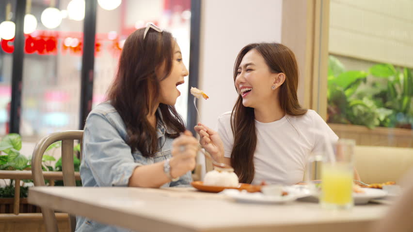 Family relationship, mother's day concept. Happy Asian mother and daughter enjoy outdoor lifestyle shopping and having lunch eating food together in restaurant at shopping mall on holiday vacation.