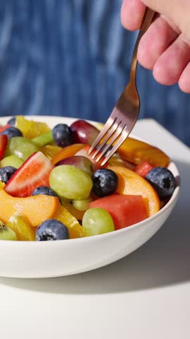 bowl of fresh fruit salad on blue background, food closeup, healthy eating