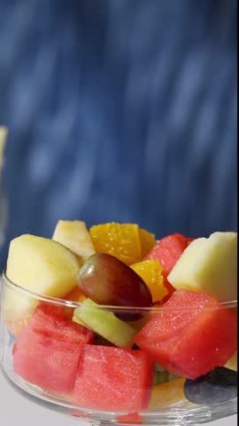 bowl of fresh fruit salad on blue background, food closeup, healthy eating
