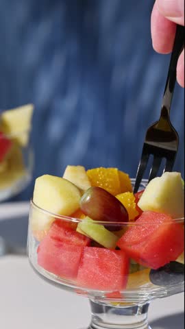 bowl of fresh fruit salad on blue background, food closeup, healthy eating