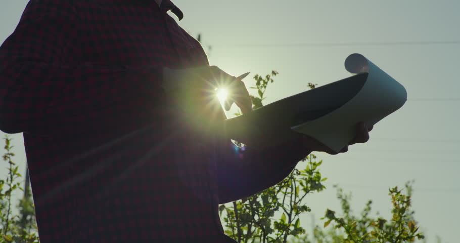 Businessman takes notes in a notebook with a beautiful sunset as background, bright sunlight filtering through his hands.