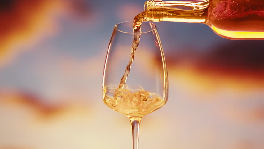Orange or white rose wine bottle and glass against a sunset in a peaceful vineyard, pouring of ecological natural wine in hotel or sunset bar restaurant, cheers friends.