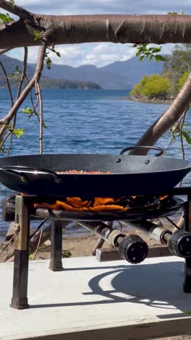 Cooking paella on an outdoor stove with Lago Lacar in Argentina as the backdrop